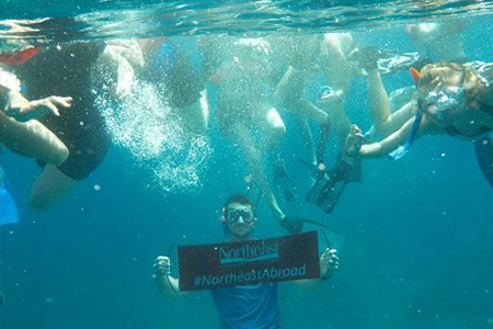 Students under water holding sign for Northeast